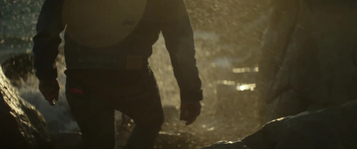 Man moving over some rocks by the shore as waves hit