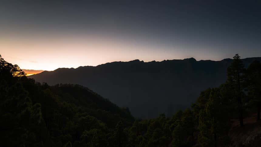 Landscape of a lake surrounded by vegetation in mountains with dense clouds passing by