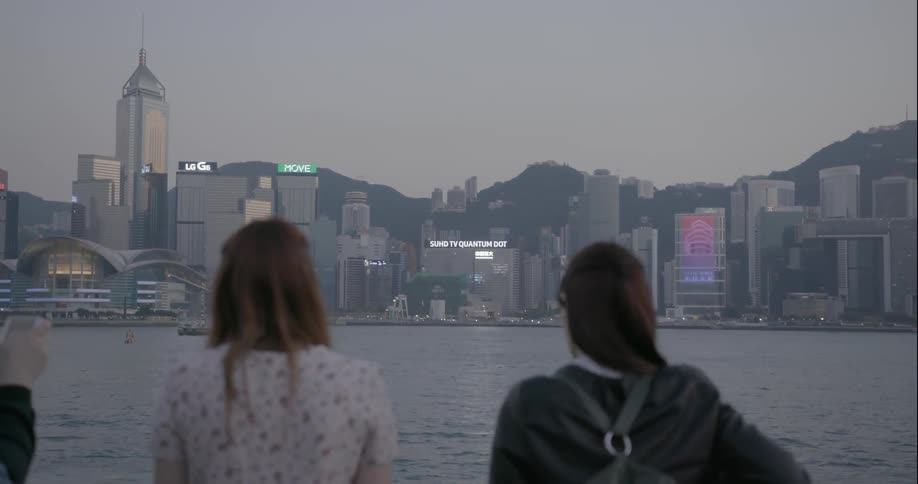 People standing along a railing and looking at a large city across the river