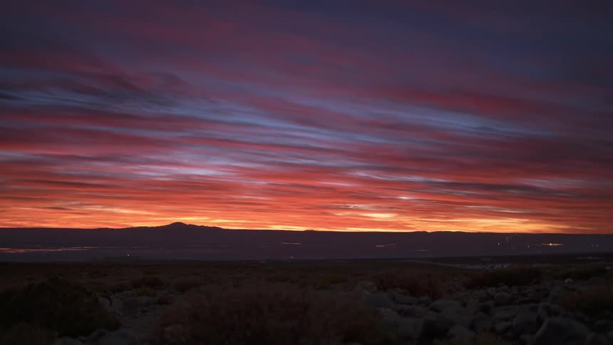 The sun is setting in the horizon of a grassland landscape