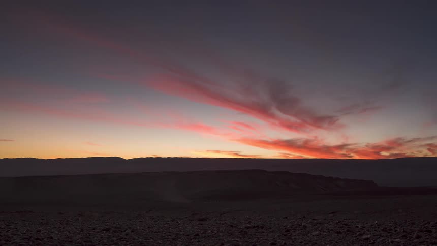 Time lapse of clouds rolling over a vast landscape at sunset