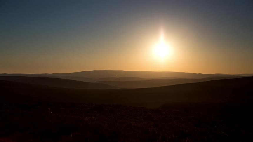 Landscape with silhouette of mountains with the sun rising and setting on the horizon