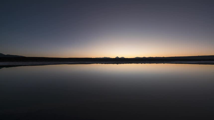 Sun rises over coastcasting sunlight across reflective water