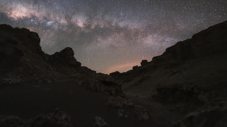 Landscape of rocky terrain with the sunset and the milky way emerging at night and then the day dawning in time lapse
