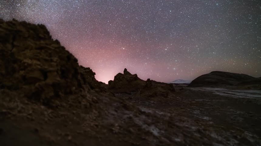 The mountainous earth rotates under a blue and pink starry sky