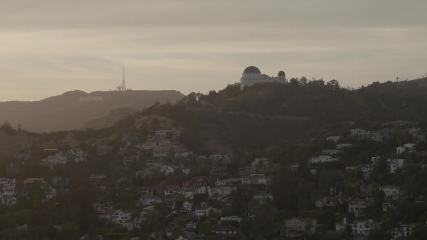 Aerial view of the suburbs of a large city on a cloudy day with an observatory on the hilltop