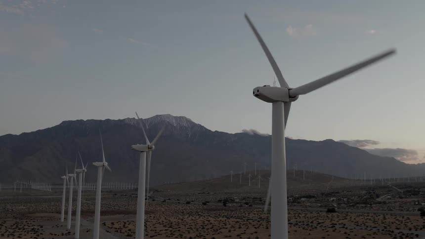 Wind turbines spinning in front of a mountain range
