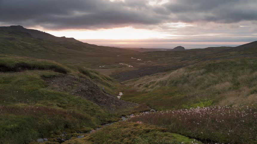 A time lapse of a grassy valley shows clouds passing overhead as the sun rises