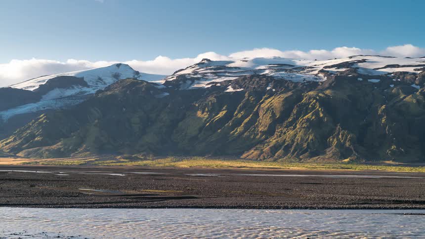 Mountainous scenery with snowcapped peaks on the edge of a lake at dawn