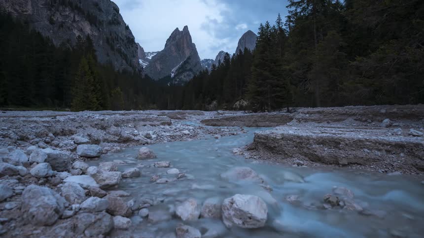 Time lapse of a river flowing near the mountains under a blue sky