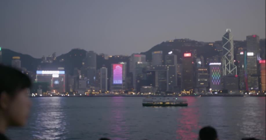 A woman photographs the hong kong skyline at dusk
