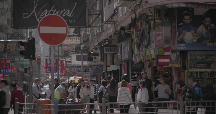 Pedestrians walk down a busy urban street,