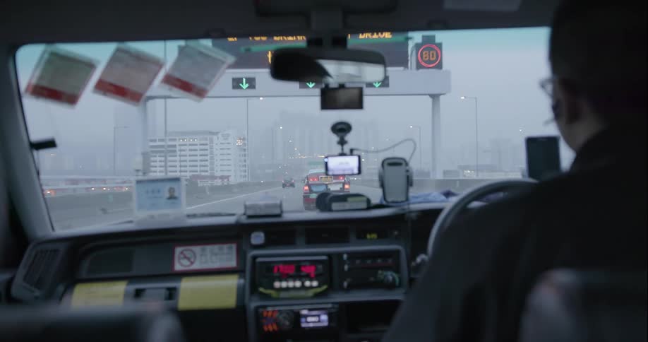 The dashboard of a taxi as it drives a highway into the city