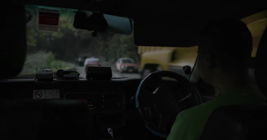 A person is driving on along a narrow, winding road with other cars
