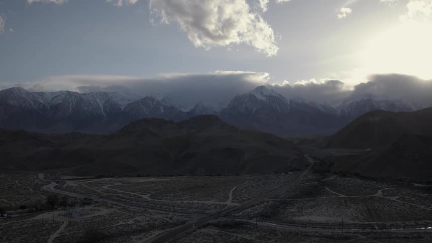 Clouds float over snow-capped mountains