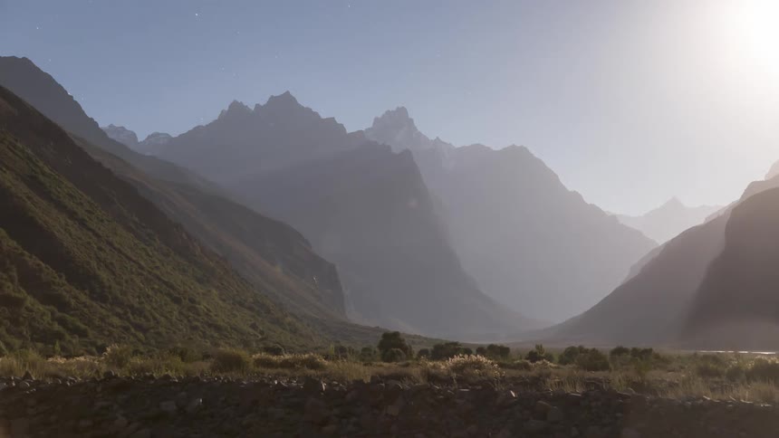 The sun moves over a mountain landscape
