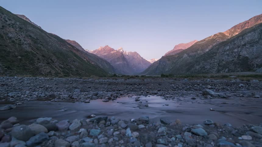 A shallow stream flows through a valley surrounded by mountains
