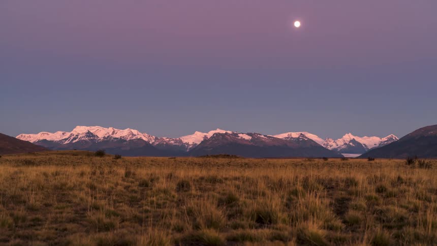 Landscape with high mountains on the horizon with the moon exposing itself and the day rising