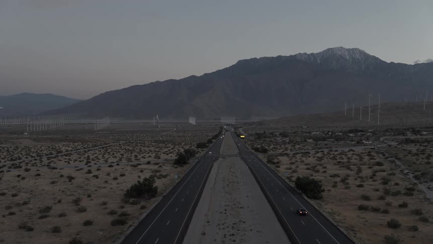 Aerial view of a highway running through barren land towards mountains