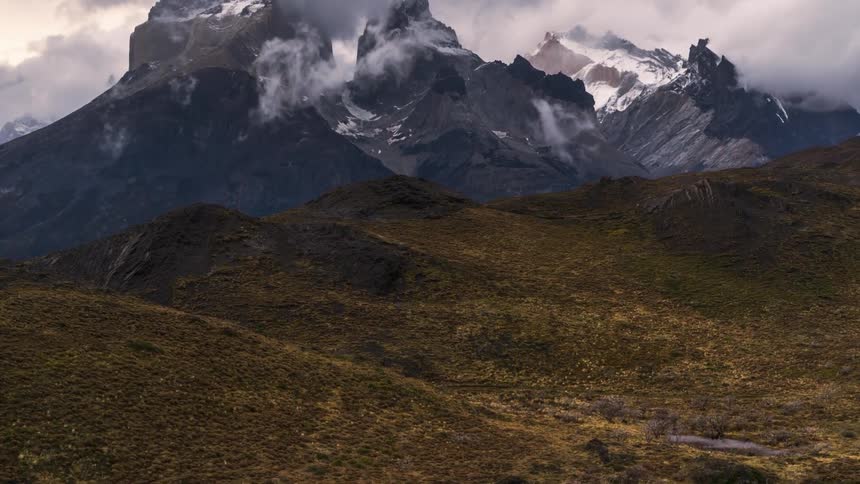 Landscape of a lake surrounded by mountains and stormy clouds