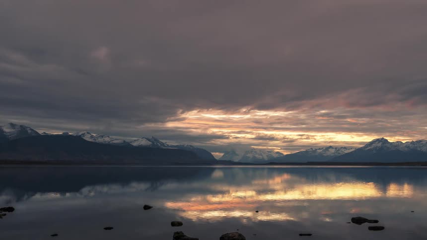 Time lapse of clouds rolling over a lake in the mountains at sunset