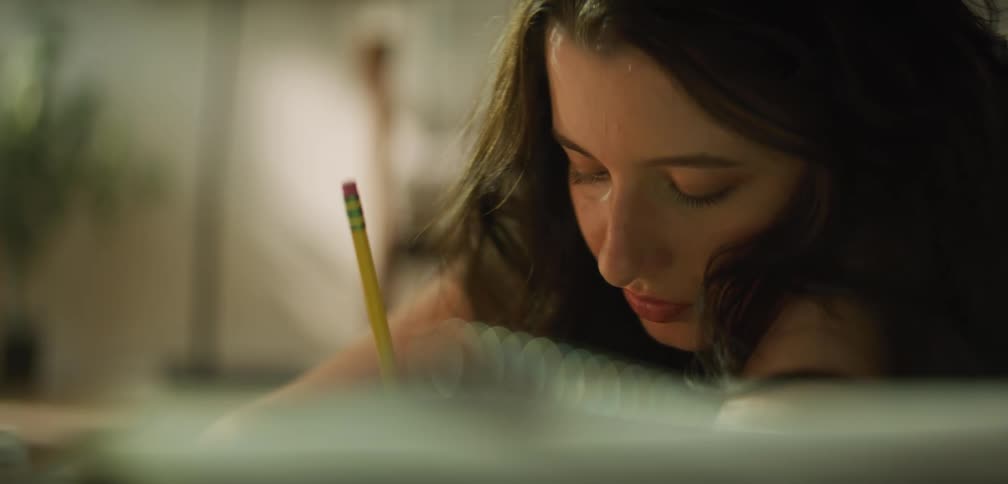 A girl is doing homework and writing with a pencil
