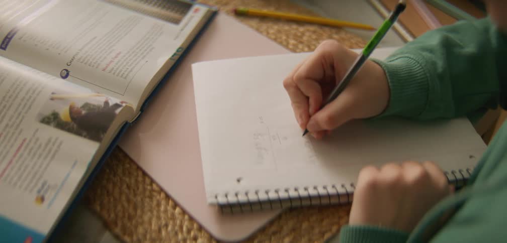 A student taking notes during a study session with textbooks