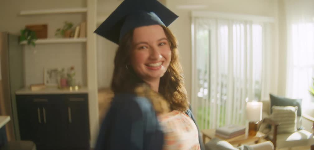 A young woman spins around in a cap and gown