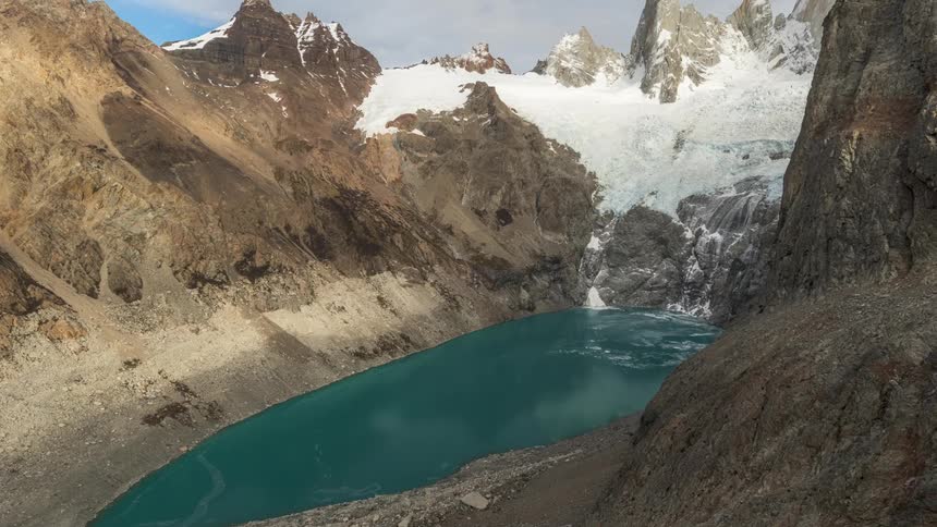 Lake begins to freeze at the base of snowy mountains