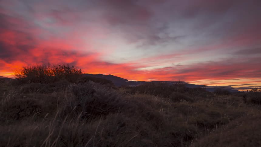 Mountainous landscape with cloudy sky changing orange and reddish tones