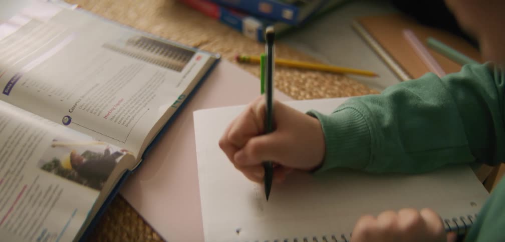Student doing homework with an open textbook in front of them