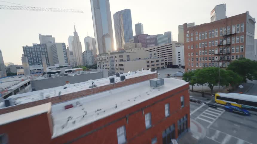 A view from a drone passing through Dallas, Texas with several buildings and cars passing in the streets