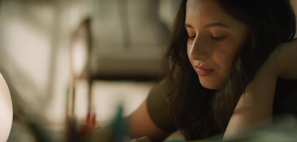 A young woman doing homework while laying across her bed