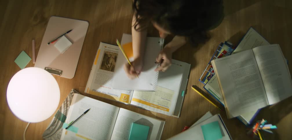 An overhead view of a person studying with an open textbook notebook and various stationery items