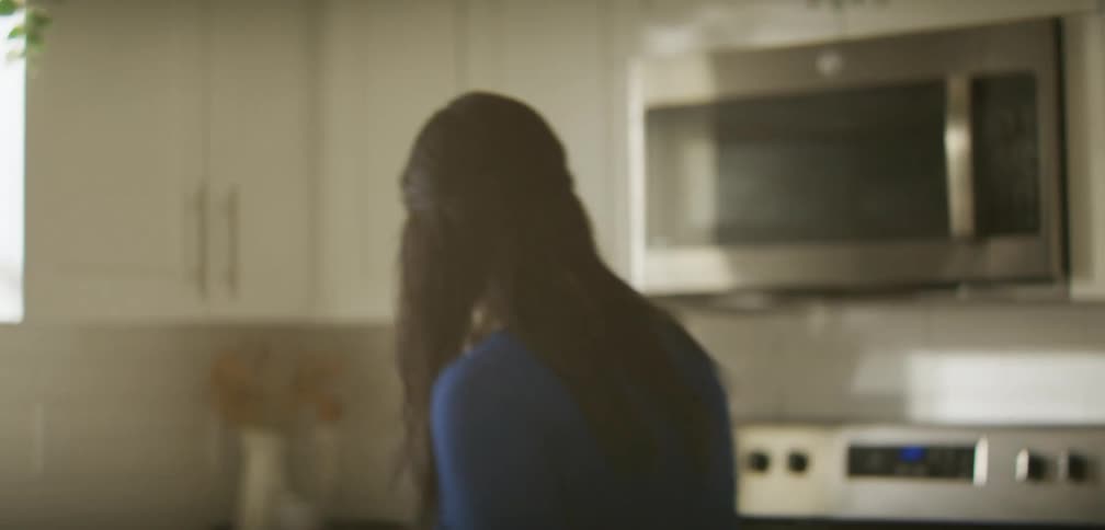 A woman is talking and walking around her kitchen