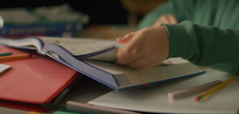 Student flips through a textbook while working on their homework