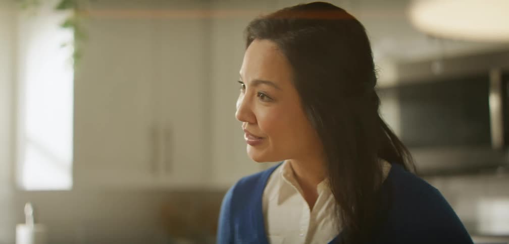 A woman is talking to someone and laughing in her kitchen
