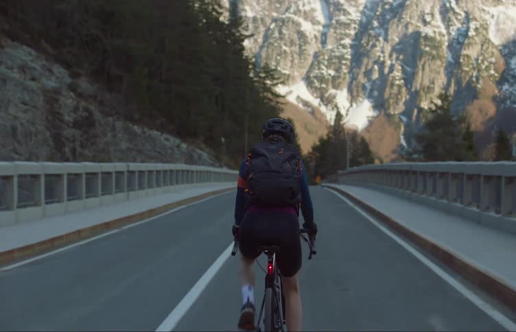 A man is biking on a street near mountains