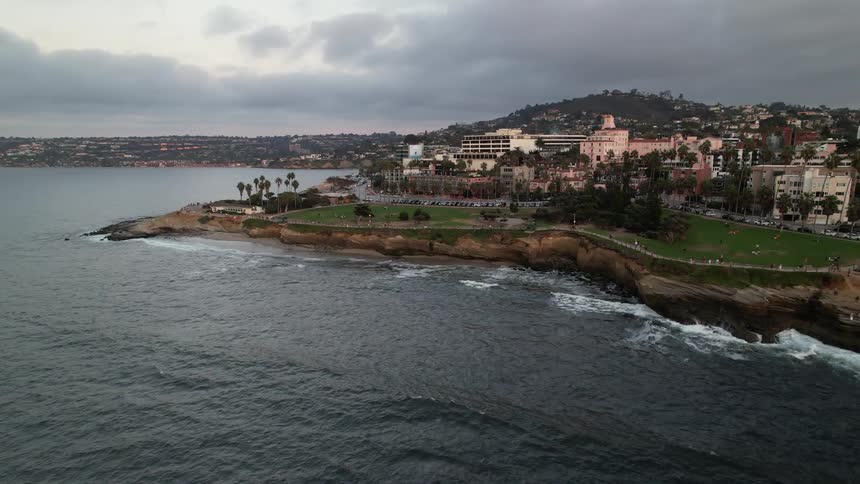 Aerial of tourists walking along an ocean overlook near a resort