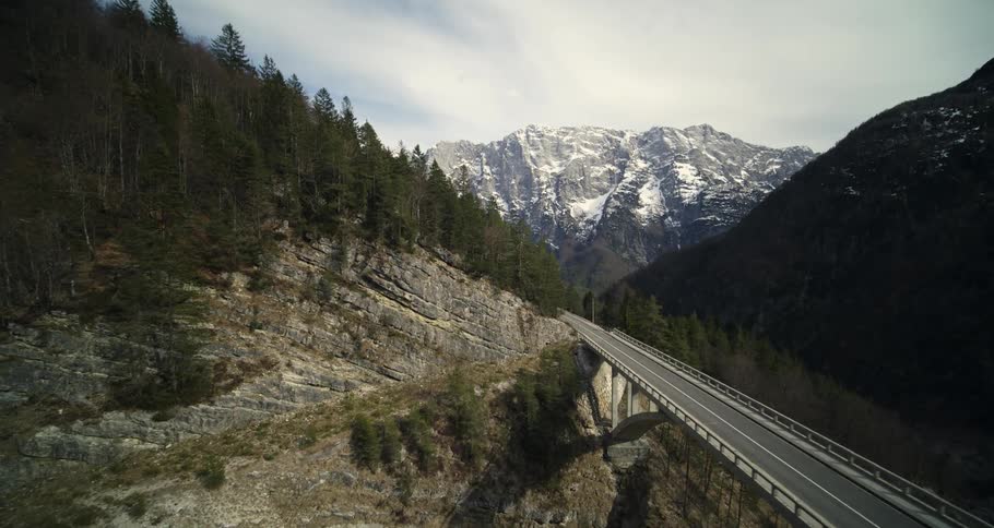 Aerial panorama of a suspension bridge between mountains with conifers on a cloudy day
