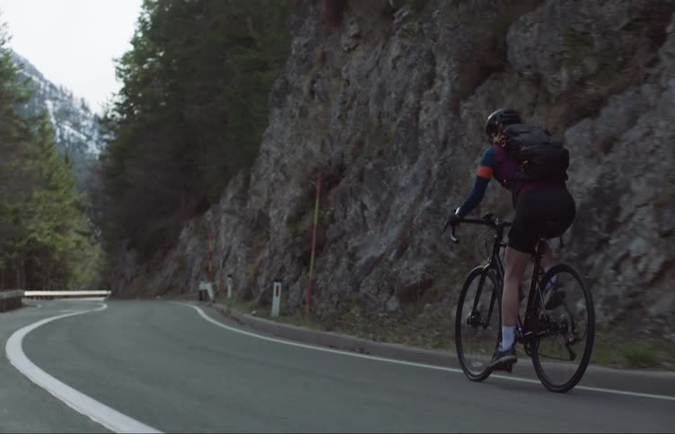 A woman is riding her bicycle on an empty rural street