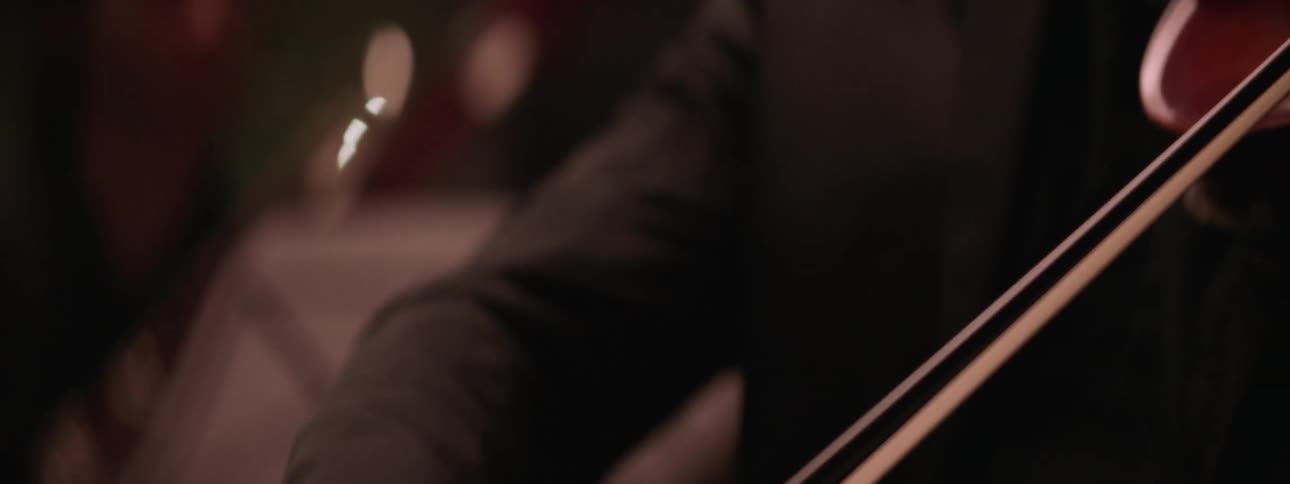 A group of people are playing string instruments indoors