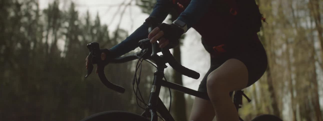 Female cyclist rides bicycle through forest