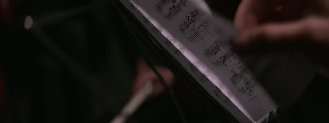 A musician flips the pages of the sheet music