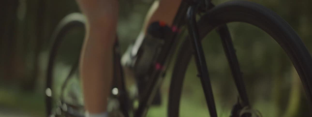 A woman is riding a bicycle outdoors in a wooded area
