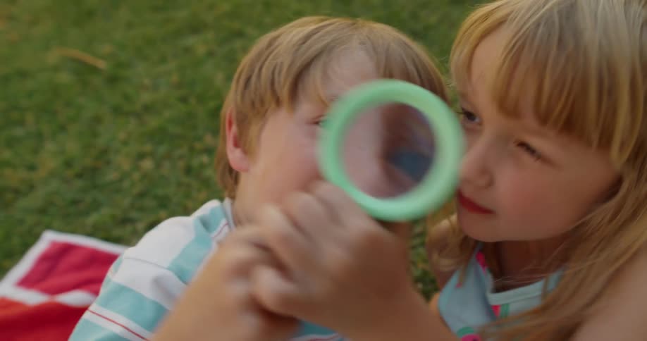 Siblings play with a magnifying glass