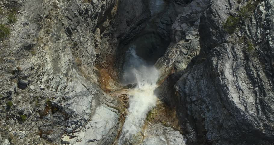 A waterfall is moving downwards against the cliff