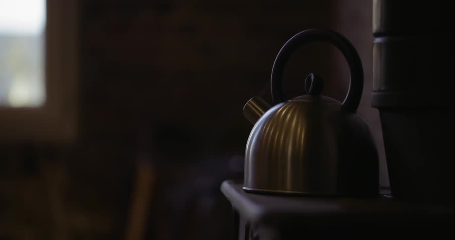 A tea kettle is steaming on a stove