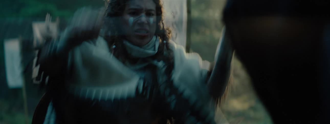A person with a painted face and wearing a white poncho raises his arms