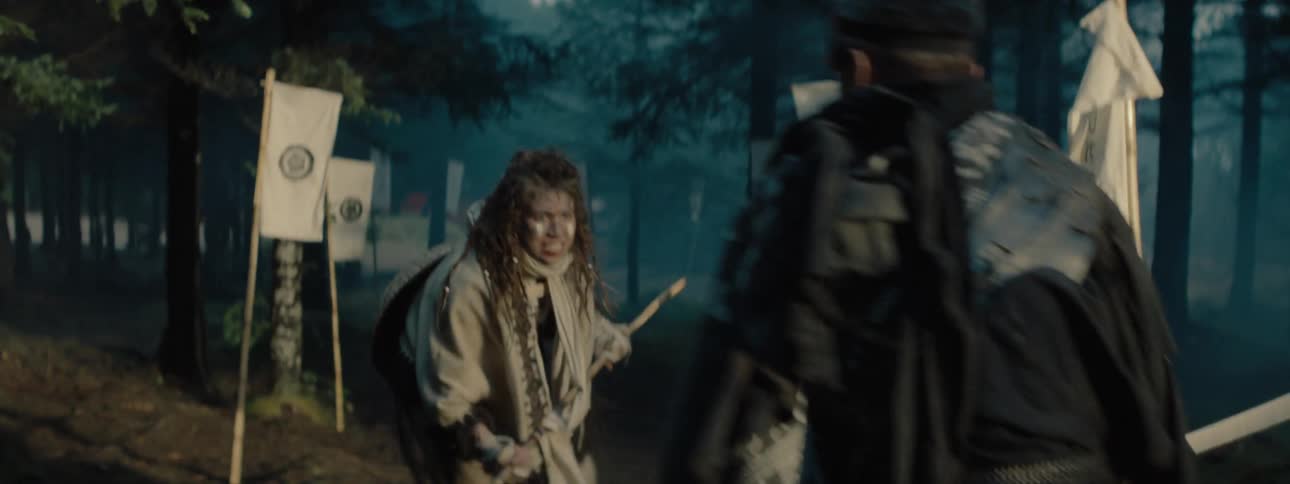 Man and woman sword fighting each other between white flags in a forest